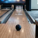 Five-pin bowling lane with slim pins and a small ball, with a smartphone and hardware wallet on a side desk