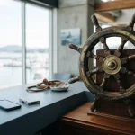Polished wooden ship helm beside a slate-blue cashier counter and a phone, photographed in clear daylight