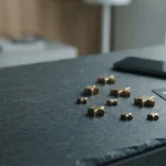 Polished brass stars arranged on a slate counter beside a smartphone and payment cards in cool daylight