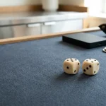 Polished dice resting on a blue felt gaming table with a small unbranded hardware wallet in the background