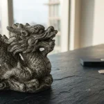 Stone dragon sculpture on a cool slate counter, with a discreet hardware wallet and coins in the background