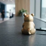 Gold-toned panda figurine on a slate counter beside a phone and unmarked payment cards in crisp daylight