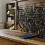 Vintage telephone switchboard with brass jack sockets and patch cords, with a smartphone and hardware wallet on the desk