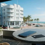 Pastel Art Deco hotel on a sunny oceanfront boulevard, with a smartphone and payment card on a slate café table