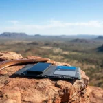 Polished wooden boomerang on a red sandstone ledge, with a smartphone and payment cards on a tray