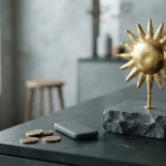 Golden sun sculpture on a slate plinth, with a hardware wallet and coins on a cashier counter
