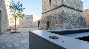 Weathered stone tower beside a modern cashier counter with a small hardware wallet in cool daylight